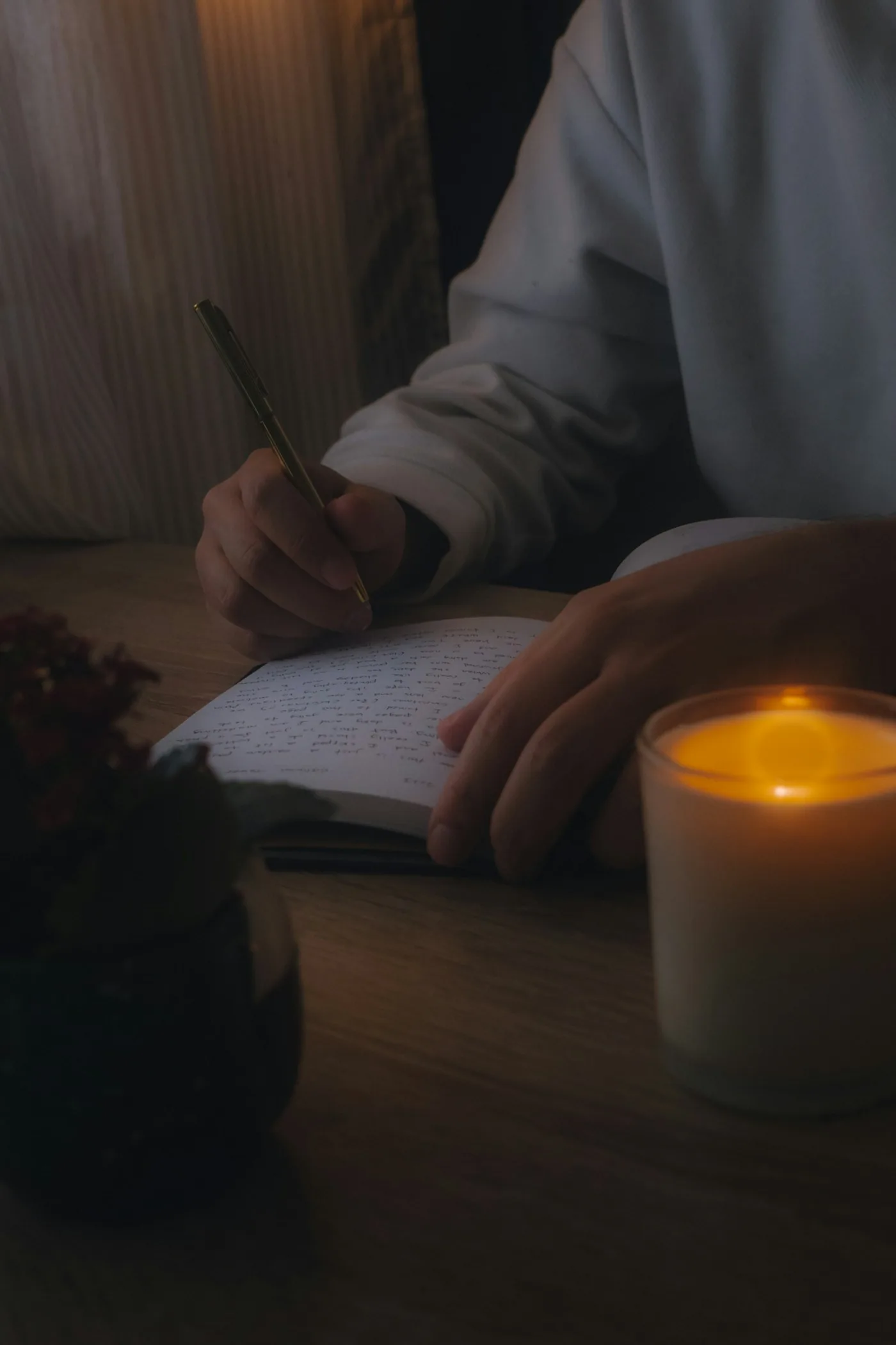 Une personne écrit dans un carnet à la lueur d'une bougie